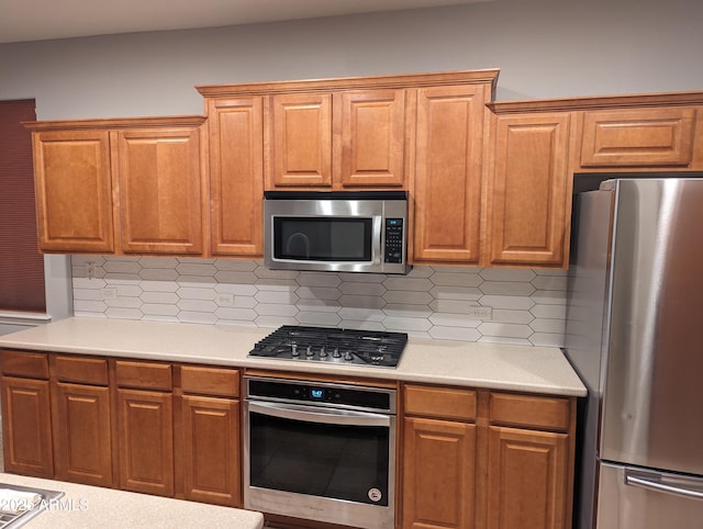 kitchen with appliances with stainless steel finishes, brown cabinets, light countertops, and tasteful backsplash