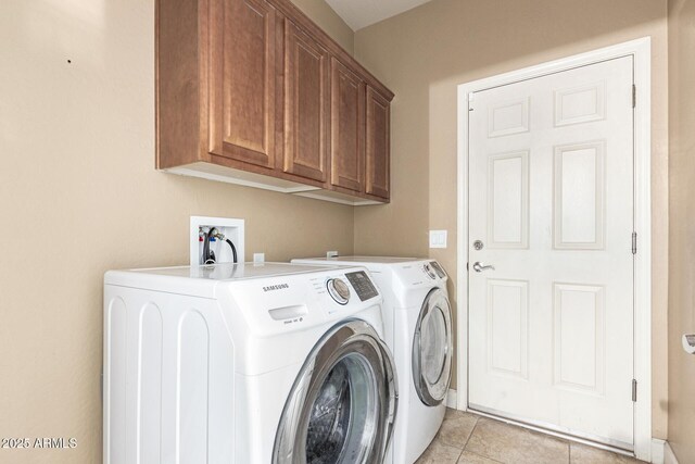 clothes washing area featuring light tile patterned floors, washer and clothes dryer, and cabinet space