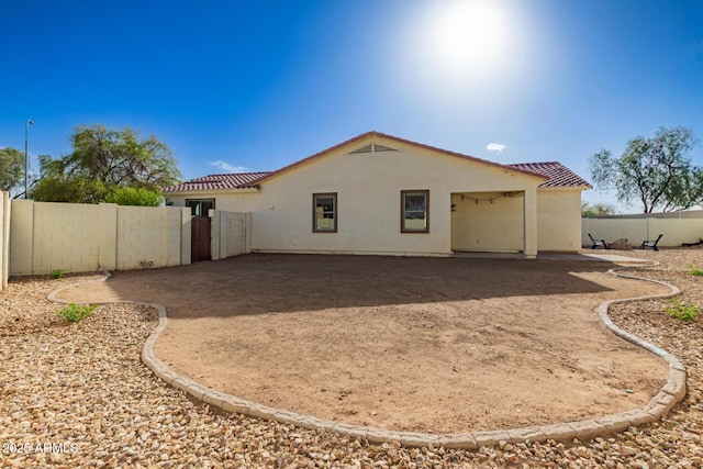 rear view of property with fence, a tiled roof, and stucco siding