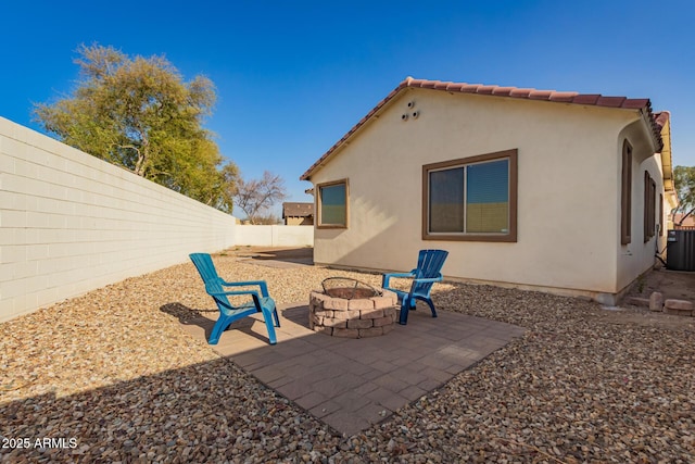 back of property with a fire pit, a fenced backyard, a tile roof, a patio area, and stucco siding