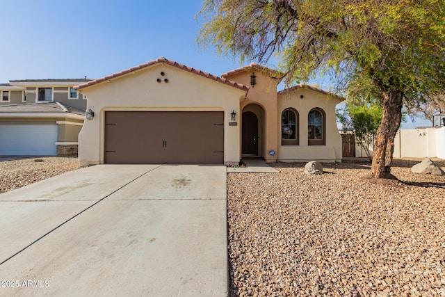 mediterranean / spanish home with driveway, a garage, a tile roof, fence, and stucco siding