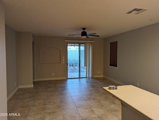 empty room with a ceiling fan, visible vents, and baseboards