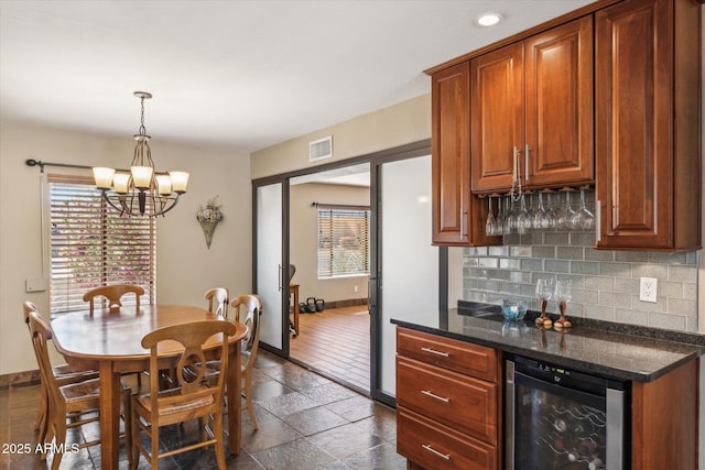 kitchen featuring decorative backsplash, decorative light fixtures, beverage cooler, and a healthy amount of sunlight