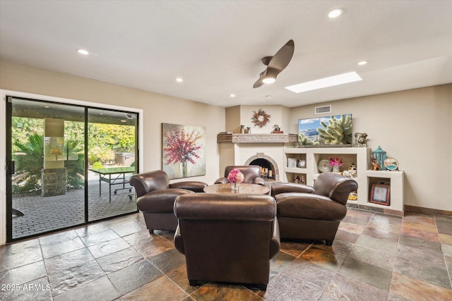 living room featuring ceiling fan and a skylight