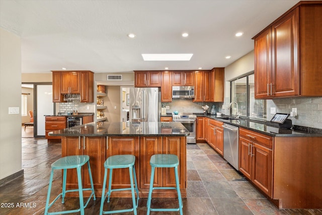 kitchen with a kitchen island, a breakfast bar, sink, beverage cooler, and stainless steel appliances