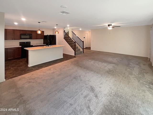 kitchen featuring dark carpet, an island with sink, sink, black appliances, and ceiling fan