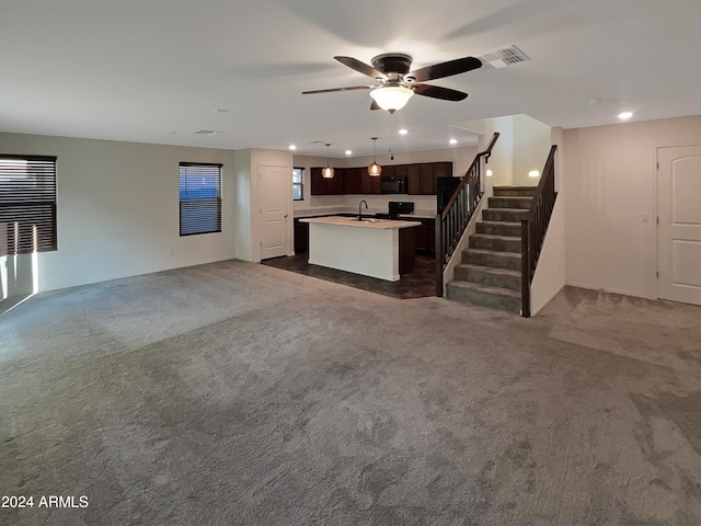 unfurnished living room with sink, dark colored carpet, and ceiling fan