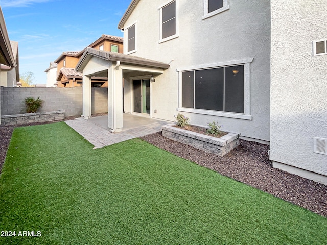 rear view of property with a patio and a lawn