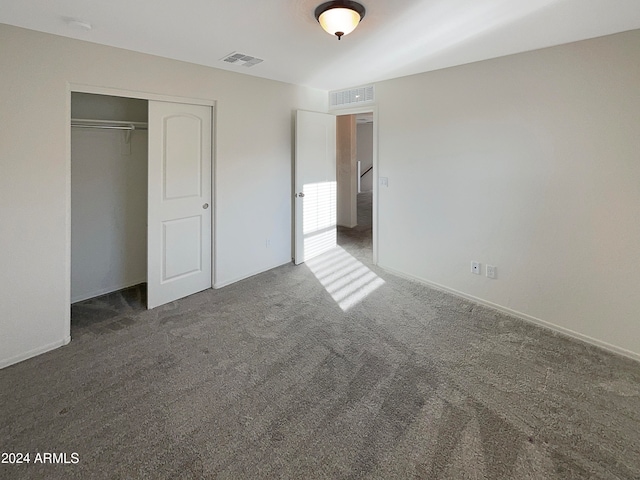 unfurnished bedroom featuring dark carpet and a closet