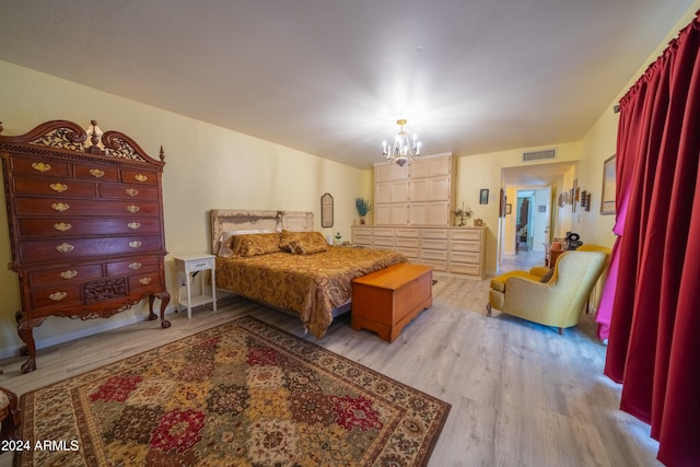 bedroom with light hardwood / wood-style floors and a notable chandelier