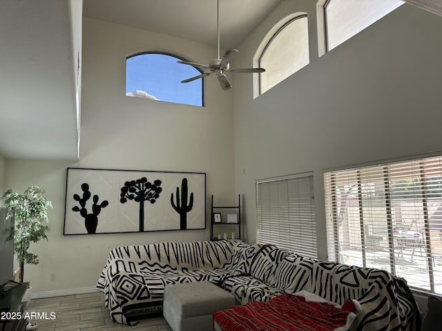 living room featuring ceiling fan, light wood-type flooring, and a towering ceiling