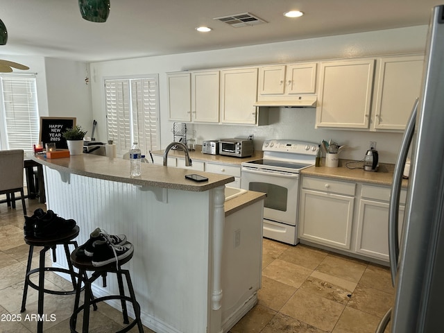 kitchen with stainless steel refrigerator, electric range, a breakfast bar, and white cabinets