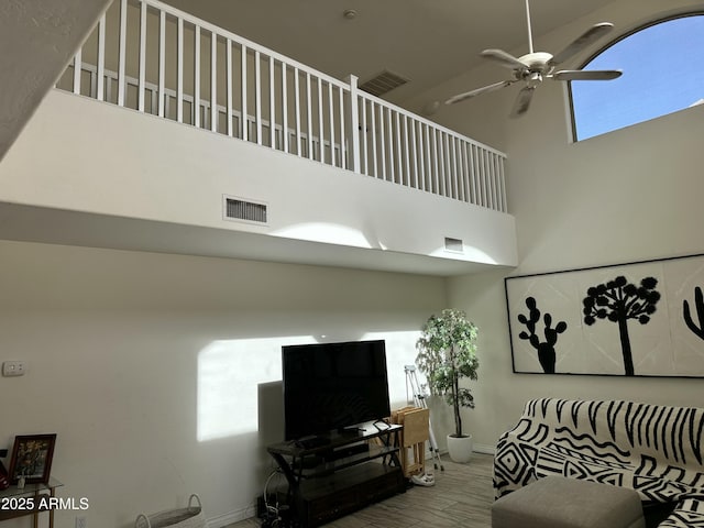 living room with a towering ceiling and ceiling fan