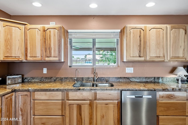 kitchen featuring sink, light brown cabinets, stainless steel dishwasher, and dark stone counters