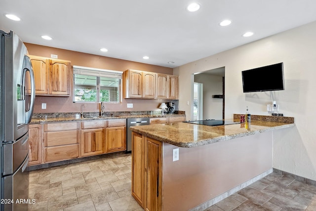 kitchen featuring kitchen peninsula, light stone counters, sink, and appliances with stainless steel finishes