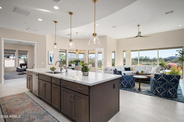 kitchen with light stone counters, dishwasher, decorative light fixtures, ceiling fan, and sink