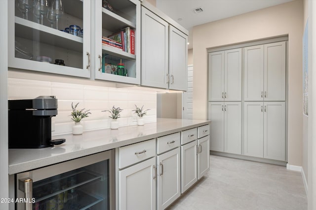 bar featuring light stone countertops, gray cabinetry, beverage cooler, and tasteful backsplash