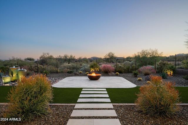 yard at dusk featuring an outdoor fire pit and a patio area