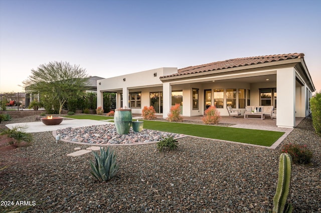 back house at dusk featuring outdoor lounge area and a patio