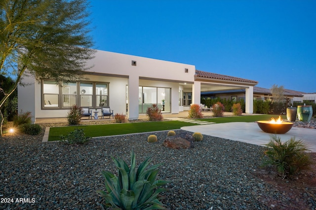 rear view of property featuring an outdoor fire pit and a patio