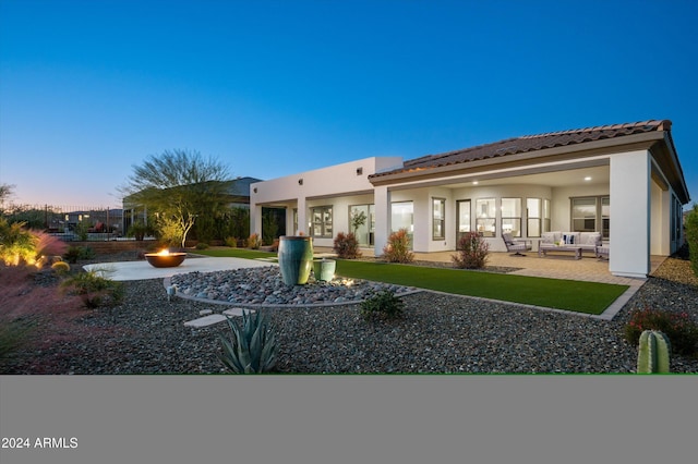 back house at dusk with a patio area, a yard, and an outdoor living space