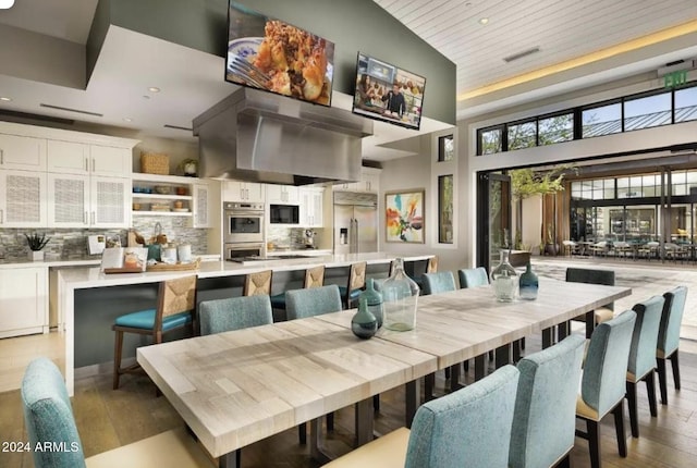 dining area featuring light hardwood / wood-style floors, wood ceiling, and high vaulted ceiling