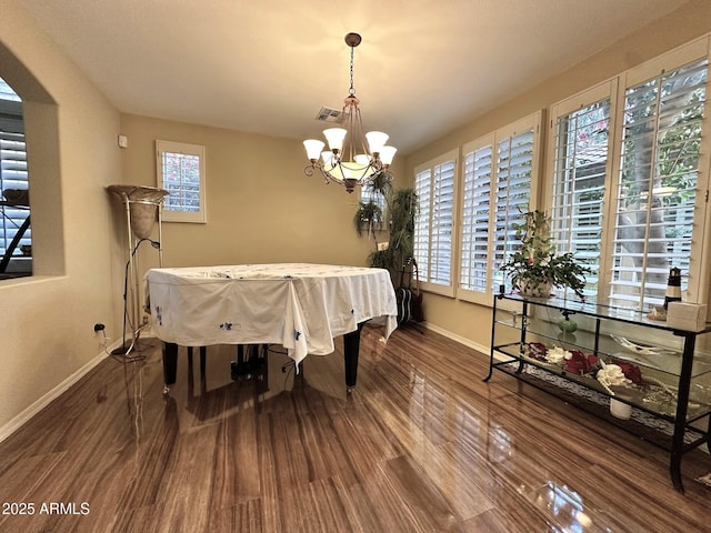 dining area with visible vents, baseboards, an inviting chandelier, and wood finished floors