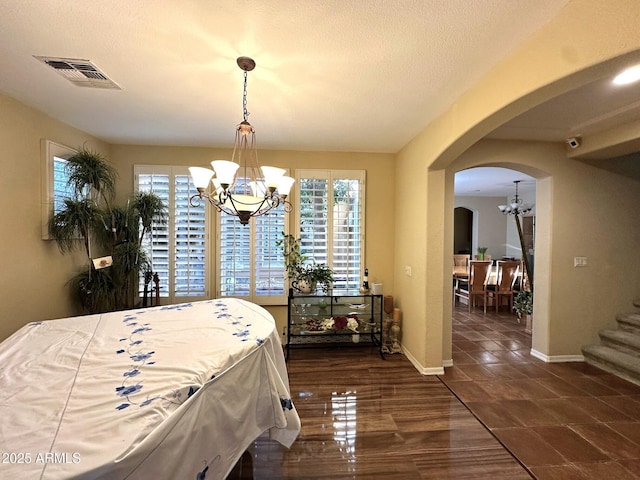 bedroom featuring an inviting chandelier, arched walkways, visible vents, and a textured ceiling