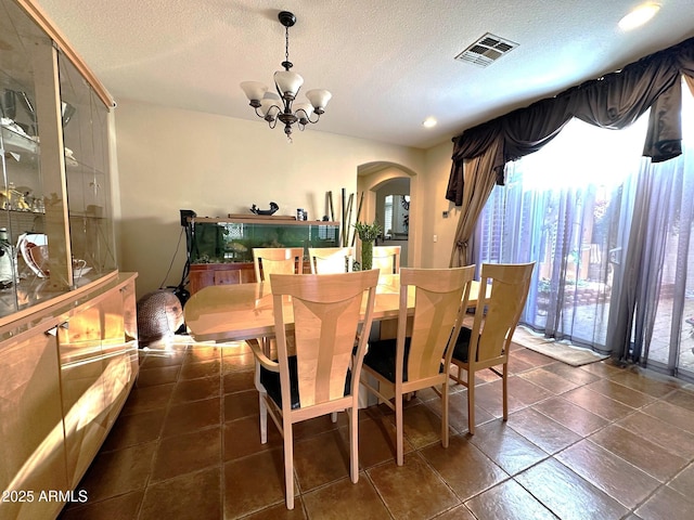 dining area with an inviting chandelier, arched walkways, visible vents, and a textured ceiling