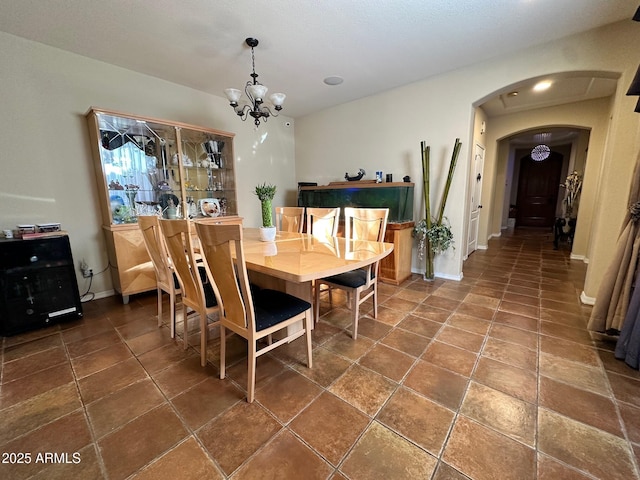 dining space featuring a notable chandelier, baseboards, and arched walkways