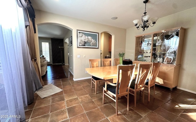 dining area with baseboards, arched walkways, and a chandelier