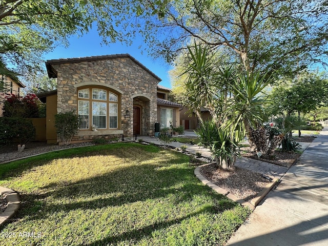 view of front facade with stucco siding, stone siding, a front lawn, and a tiled roof