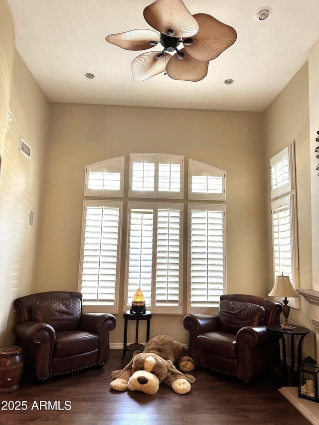 living area with visible vents, a ceiling fan, and wood finished floors