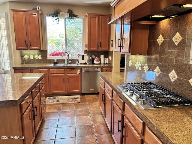 kitchen with tile countertops, a sink, decorative backsplash, appliances with stainless steel finishes, and wall chimney range hood