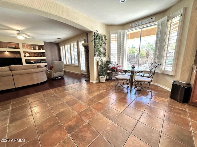 dining space featuring built in features, baseboards, ceiling fan, and a fireplace