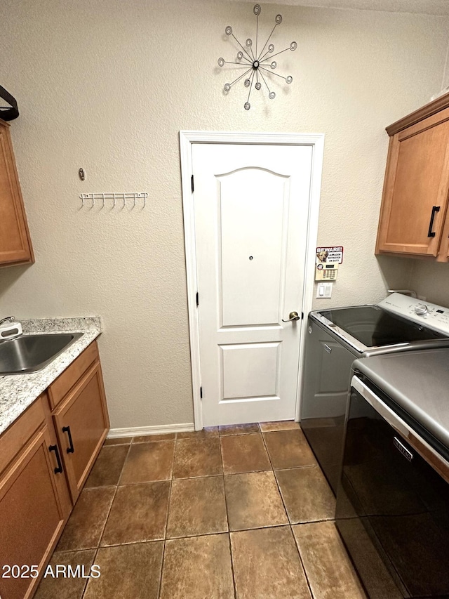 washroom with baseboards, cabinet space, a sink, dark tile patterned floors, and independent washer and dryer