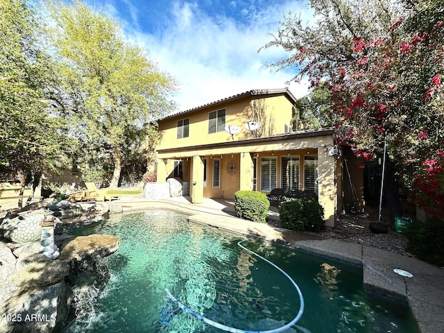 rear view of house featuring an outdoor pool, stucco siding, and a patio