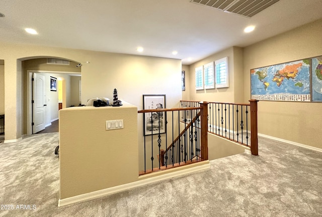 hall featuring visible vents, an upstairs landing, recessed lighting, arched walkways, and carpet floors