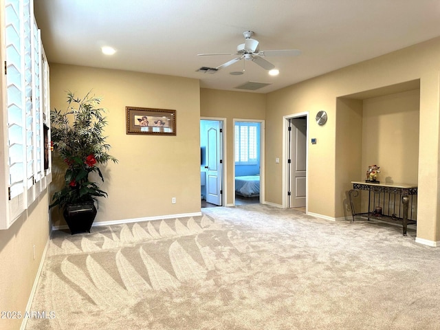 interior space with visible vents, baseboards, light colored carpet, and a ceiling fan