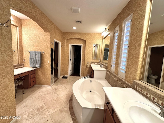 full bathroom featuring visible vents, toilet, two vanities, a sink, and a bath