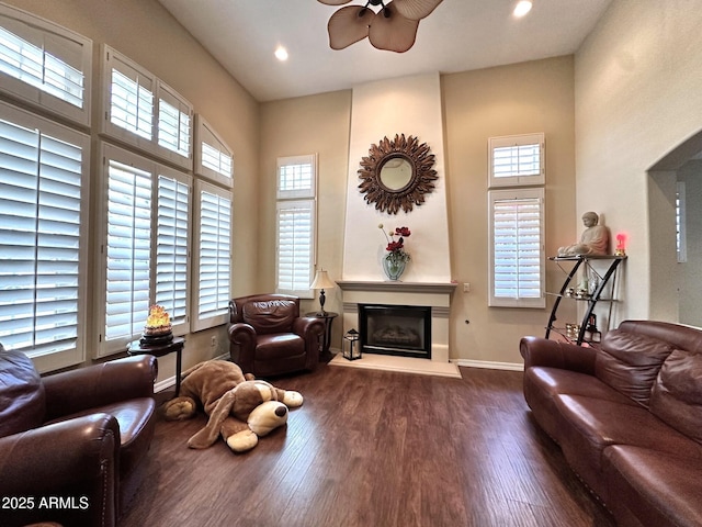 living room with a wealth of natural light, a glass covered fireplace, baseboards, and wood finished floors