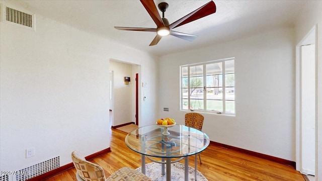 dining space with baseboards, visible vents, ceiling fan, and wood finished floors