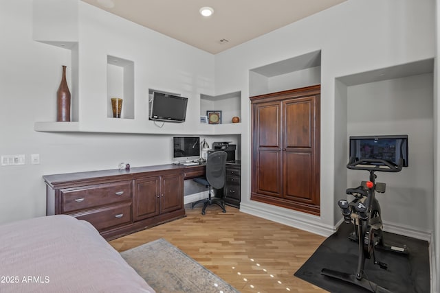 bedroom with baseboards, built in study area, and light wood finished floors