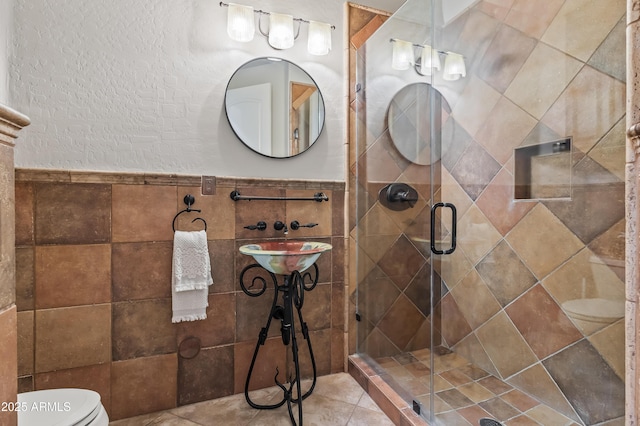 full bathroom with toilet, wainscoting, and a shower stall