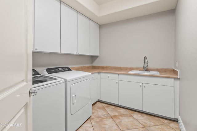 clothes washing area with cabinet space, light tile patterned floors, washing machine and dryer, and a sink