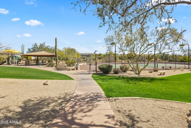 view of property's community featuring a tennis court, fence, playground community, a gazebo, and a yard