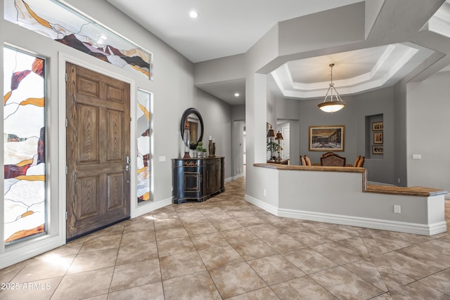 entrance foyer featuring light tile patterned flooring, recessed lighting, a tray ceiling, and baseboards