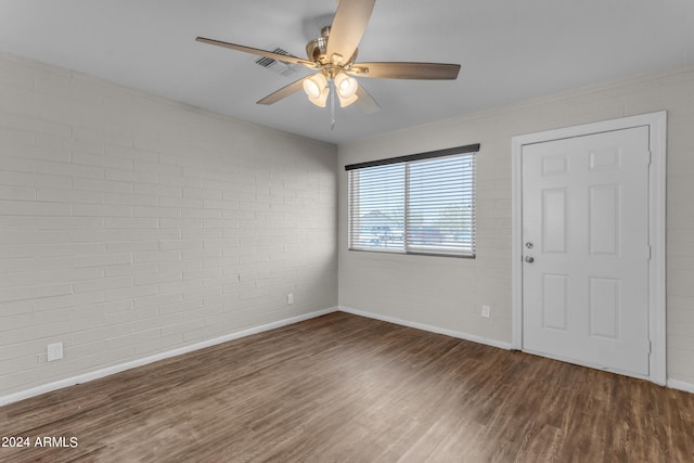 unfurnished room with brick wall, dark hardwood / wood-style floors, and ceiling fan