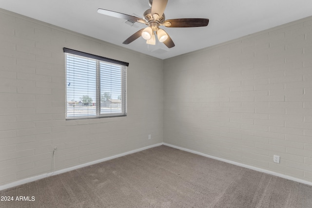 carpeted spare room with crown molding, ceiling fan, and brick wall