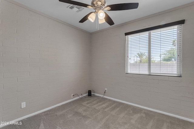 empty room featuring carpet flooring, brick wall, ceiling fan, and crown molding